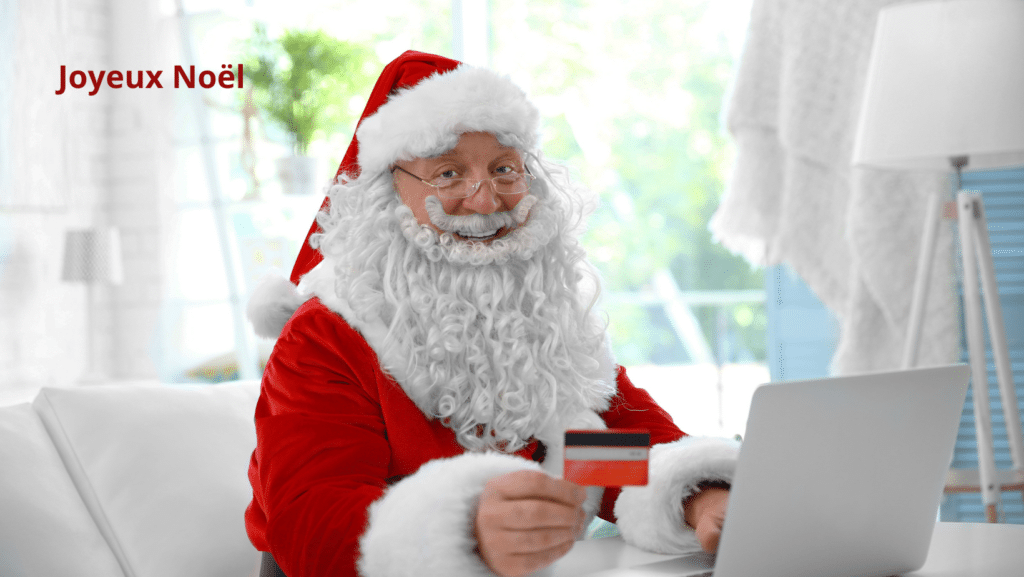 Père noël qui fait du shopping en ligne avec sa carte de crédit à la main